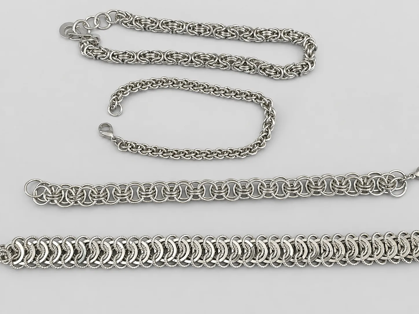 Four stainless steel bracelets showing Byzantine, Jens Pind Linkage, Helm, and Vertebra weaves