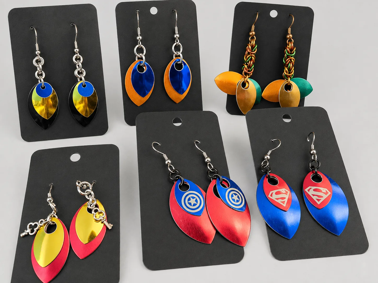 Assorted colorful scale earrings on black display cards