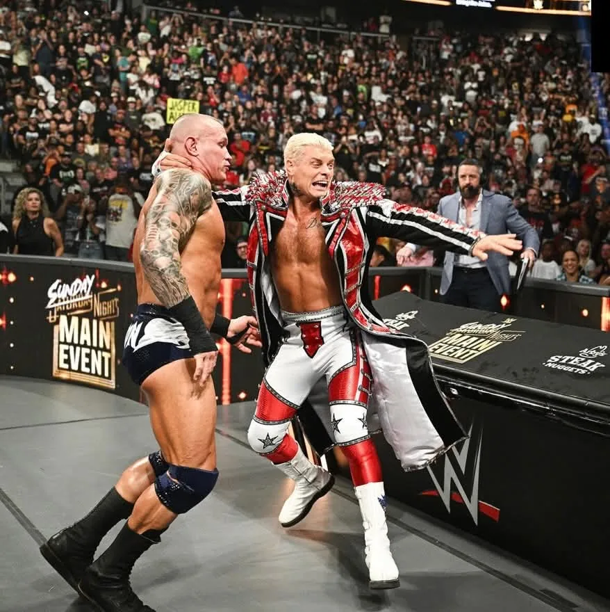 Cody Rhodes at ringside in a red, black, and silver entrance coat with KrakenMaille scale shoulder detailing
