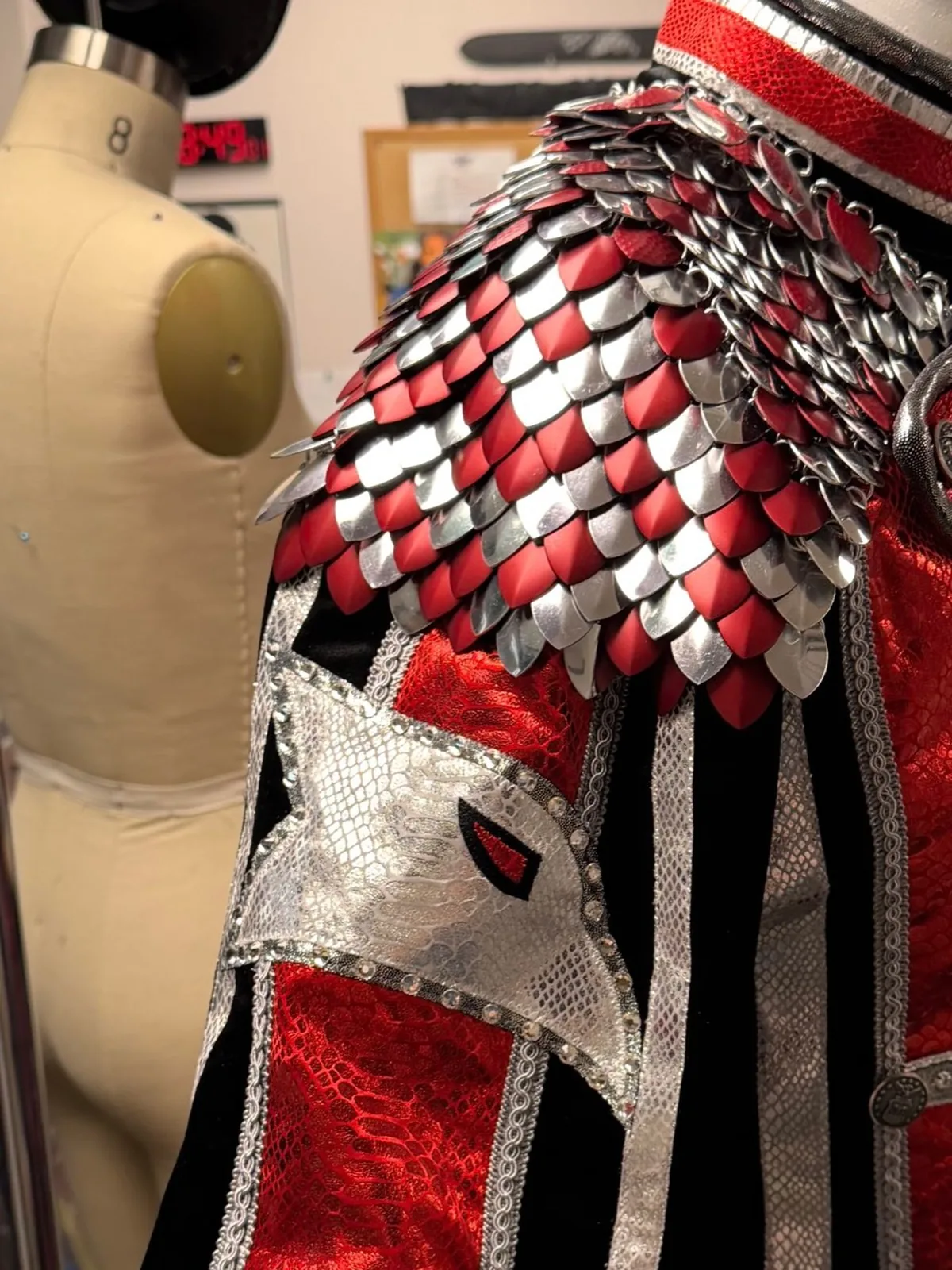 Close-up of layered red and silver KrakenMaille scales on the shoulder of a Cody Rhodes entrance coat